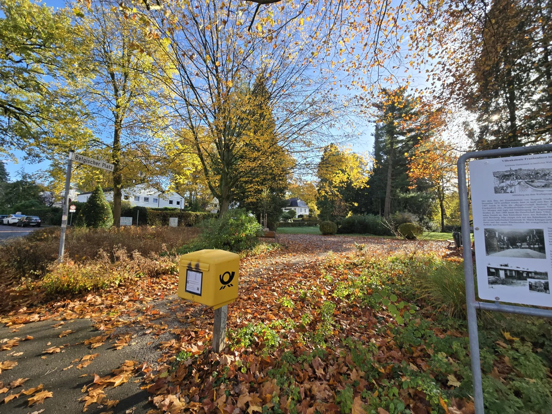 Belgischer Platz in Frankenforst mit Bäumen und Blick Richtung Haltestelle, November 2025
